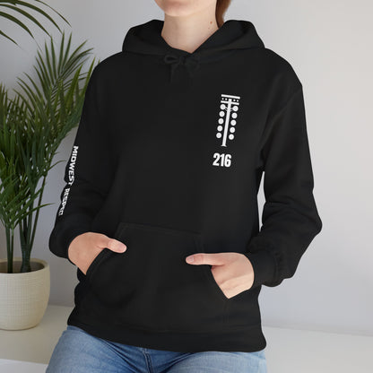 Person wearing a black hoodie with a small graphic on the chest, standing against a neutral background.