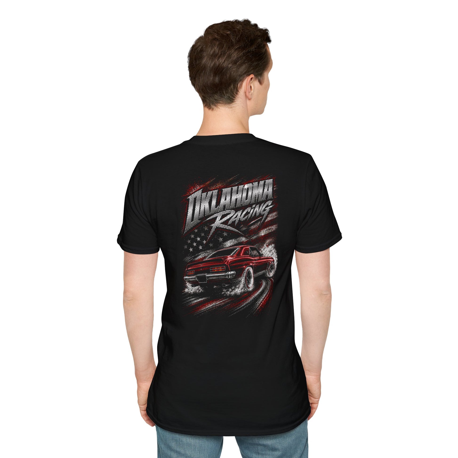 A man viewed from the back wearing a black short-sleeve t-shirt with a large graphic on the back. The graphic features the text 'Oklahoma Racing' in stylized white and red lettering above an illustration of a red race car with a distressed American flag background.