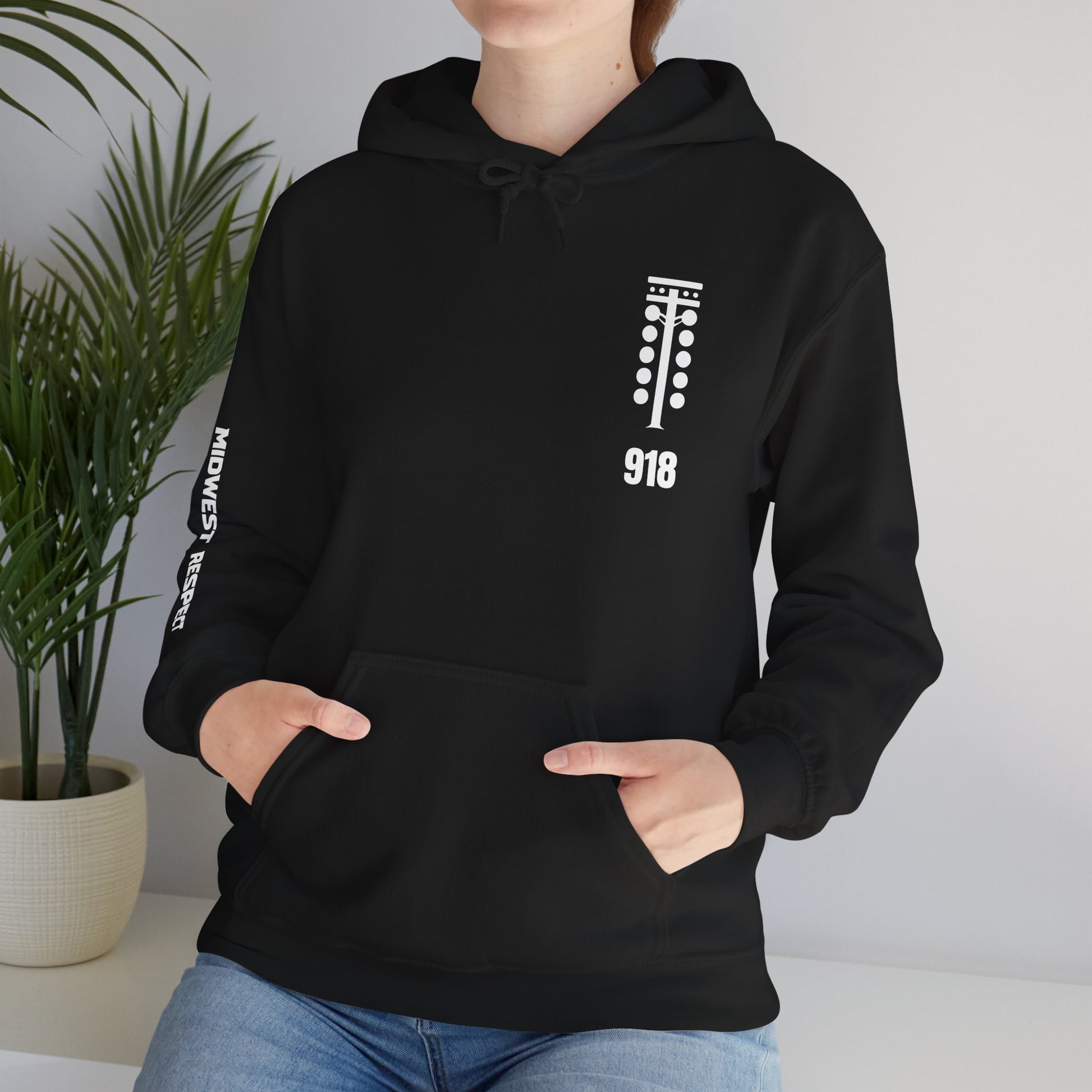 Person wearing a black hoodie with a small graphic on the chest, standing against a neutral background.