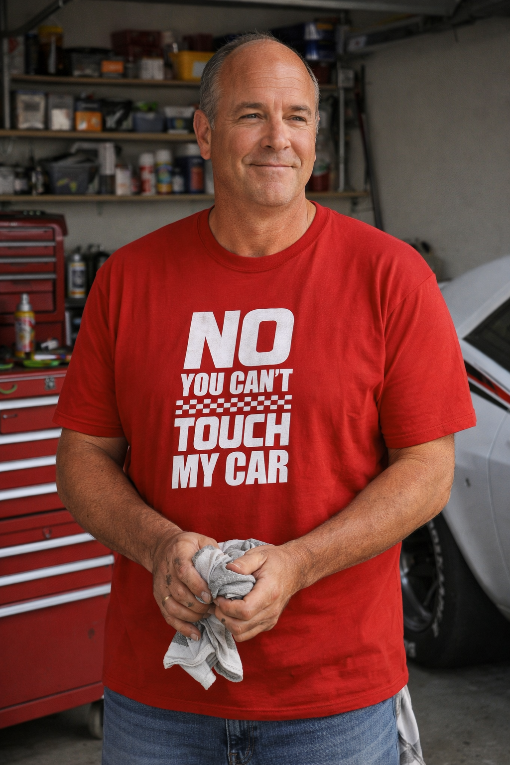 Man wearing a red t-shirt with 'NO YOU CAN'T TOUCH MY CAR' text in a garage.