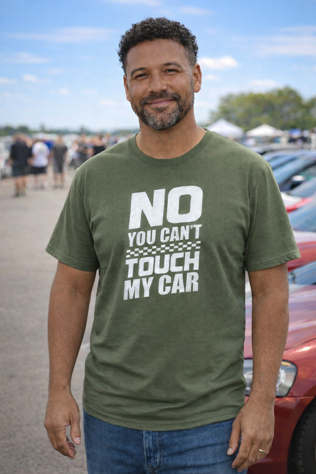 Man wearing a green t-shirt with 'NO YOU CAN'T TOUCH MY CAR' text in a parking lot.