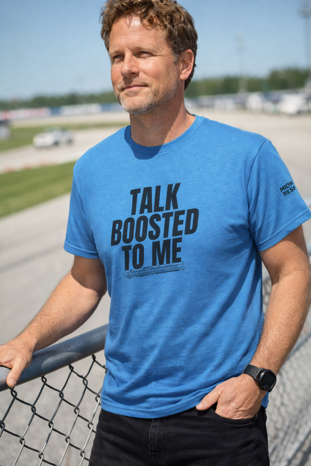 Man wearing a blue t-shirt with text standing on a racetrack.